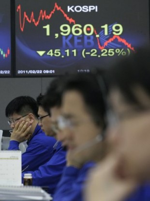 Currency traders sit in front of a screen showing the Korea Composite Stock Price index, which fell today by 1.76 per cent before closing.