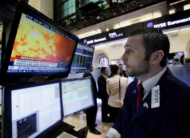 Specialist Christopher Gildea watches images from the earthquake in Japan on a television screen at his post on the floor of the New York Stock Exchange