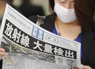 A masked woman wears a newspaper with a banner headline: