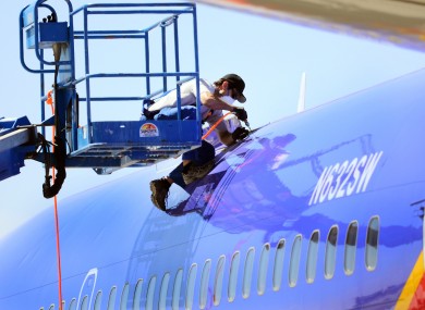 A worker investigating the emergency landing of Southwest Airlines flight 812 cuts away a portion of the plane's fuselage in Arizona yesterday.