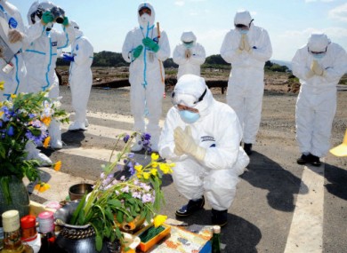 15 May 2011: The governor of Fukushima and others wearing radiation protection suits offer prayers for the victims of the 11 March disasters.