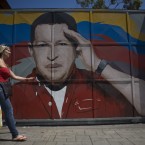 A woman walks by a gate with a painting depicting Venezuela's President Hugo Chavez, who today admitted he is suffering from cancer (AP Photo/Ariana Cubillos)