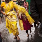 An Indian girl covers herself with her mother's sari during heavy rains in Dharmsala, India (AP Photo/Kevin Frayer)