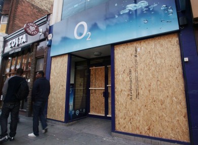 An o2 shop is boarded up after being looted in last week's riots in London.