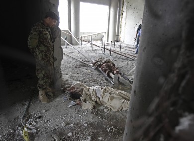 Afghan military personnel watch two dead bodies killed during a gun battle with Afghan and NATO forces.
