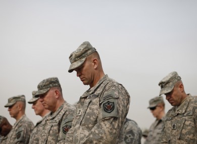 Military personnel bow their heads during ceremonies marking the end of the war in Iraq today.