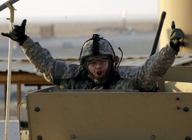 A soldier gestures from the gun turret of the last vehicle in a convoy at the Kuwaiti border