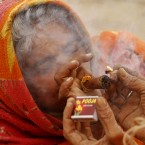 A Hindu women smokes marijuana as she sits at the confluence of rivers Ganges, Yamuna and mythical Saraswati, on 