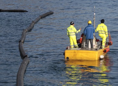 Workers inspect the booms designed to prevent oil contamination