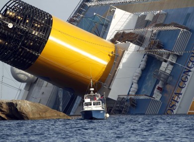 A police boat sails in front of the capsized vessel today