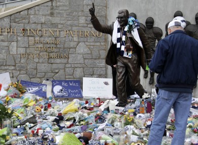A statue of legendary Penn State football coach Joe Paterno is surrounded by flowers and items left by fans today.