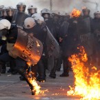 A riot police officers tries to extinguish flames from a petrol bomb thrown by protestors outside the Greek parliament, Athens. (AP Photo/Thanassis Stavrakis)