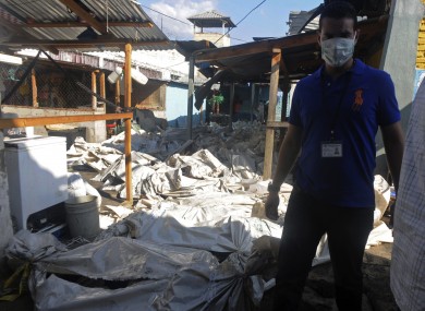 A forensic worker standing next to bags with bodies of inmates killed during the fire.