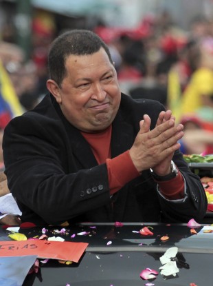 Chavez applauds as he is driven to the airport in Caracas on his way to Cuba for surgery