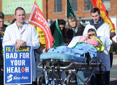 Paddy McKitterick (L) and Niall O'Leary (R) push Niamh Quigley, 9, in a hospital bed at a protest to save emergency services at St Columcille's Hospital.