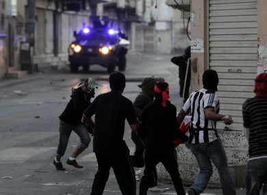 Protesters throw stones at armoured vehicles in the streets of Sanabis, on the edge of Manama, yesterday.