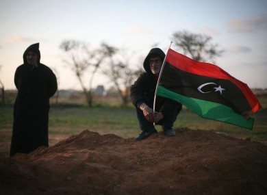 Libyan men, one waving a pre-Gaddafi flag, attend a funeral in Benghazi on Monday