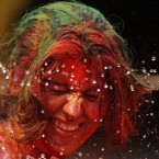 An Indian women, her face smeared with colored powder, reacts as water is squirted on her during Holi celebrations in Chennai, India. (AP Photo/Arun Sankar K.)