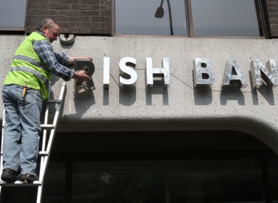 A workman removes the signage from the former Anglo Irish Bank HQ in Dublin