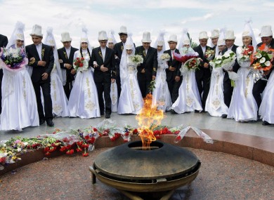 Kyrgyz couples lay flowers by the Eternal Flame in Bishkek last May before a mass wedding ceremony.