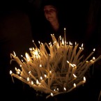 A Christian worshipper lights candles inside the Church of the Holy Sepulchre, traditionally believed to be the burial site of Jesus Christ, in Jerusalem's Old City. (AP Photo/Sebastian Scheiner)