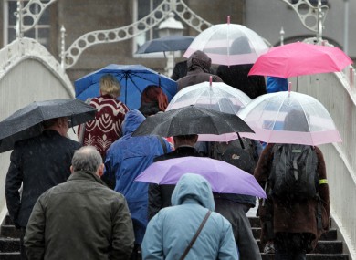 Pedestrians walk through heavy ran over the Ha' Penny Bridge in Dublin