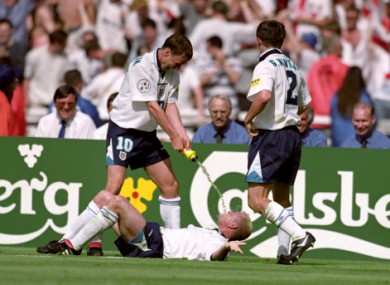 England's Paul Gascoigne re-enacts the infamous Dentist's Chair incident with Teddy Sheringham at Euro '96. Gary Neville looks on.