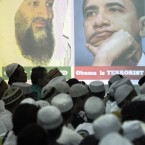 Members of hardline group Islam Defenders Front (FPI) gather by portraits of Osama Bin Laden and Barack Obama projected on a screen at their headquarters in Jakarta, Indonesia, Wednesday, May 4, 2011. (AP Photo/Irwin Fedriansyah)