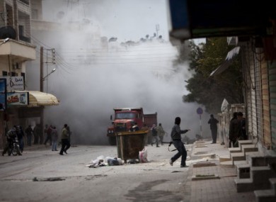 Syrian rebels amid smoke after a tank fired in Idlib, 11 March 2012.