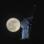The full moon rises behind a Statue of Liberty replica atop a hotel in Kosovo's capital Pristina ( AP Photo / Visar Kryeziu )