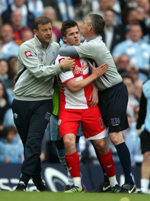 QPR's Joey Barton is escorted from the pitch.