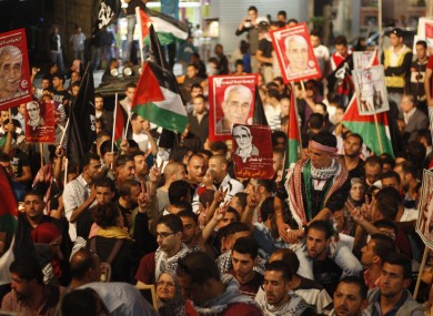 Palestinians hold pictures of prisoners and Palestinian flags as they celebrate the end of a prisoners' hunger strike in Israeli jails, in the West Bank city of Ramallah