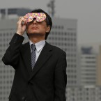 A business man watches the eclipse at a waterfront park in Yokohama, near Tokyo (AP Photo/Shuji Kajiyama)