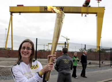 Karen Marshall, the first torch bearer from Northern Ireland, poses with the Olympic torch in front of Harland & Wolff shipyard this morning.