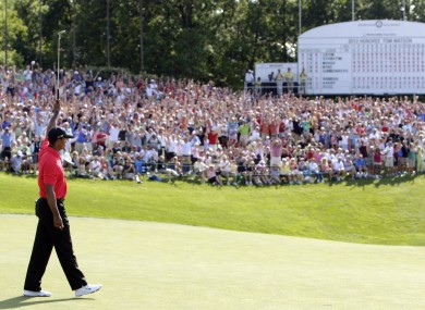 Tiger Woods raises his putter after making a birdie putt on the 18th hole