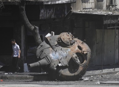 A Syrian man walks next to part of a destroyed military tank on the outskirts of Idlib in Syria