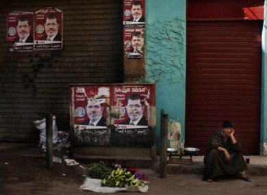 An Egyptian street vendor awaits customers in Cairo by campaign posters for Morsi.