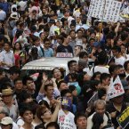 A taxi is surrounded by protesters as tens of thousands of Hong Kong residents march at a down town street (AP Photo/Vincent Yu)