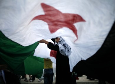 A Syrian girl lifts the center of a giant revolutionary flag during a protest against Bashar Assad, in front the Syrian embassy in Amman, Jordan.