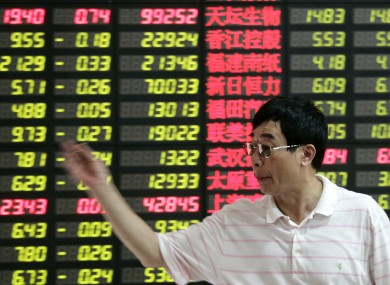 An investor gestures in front of the stock price in Shanghai, China this month