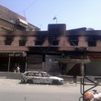 This citizen journalist image shows the Syrian revolutionary flag flying over a gutted police station. (AP Photo)