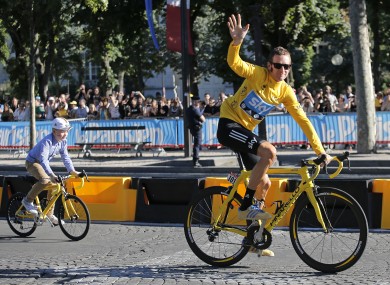 Wiggins cycling race rides up the Champs Elysees with his son during a parade after the last stage of the race in Paris.