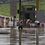 Workers puts sandbags to block flood water entering the toll gate in Fangshan district of Beijing (AP Photo/Andy Wong)