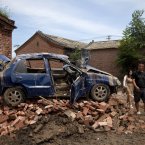 Chinese people walk past a flood damaged vehicle on the bricks at a village in Fangshan district of Beijing (AP Photo/Andy Wong)