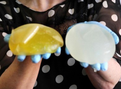 A woman whose PiP impants ruptured shows the removed implants.