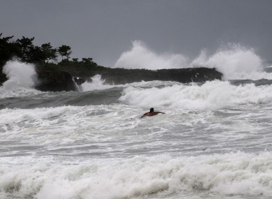 A surfer swims out to sea at Manresa beach as Tropical Storm Isaac approaches Santo Domingo, Dominican Republic