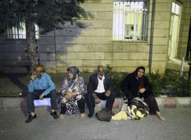 Residents sit at the side of a street after the earthquake