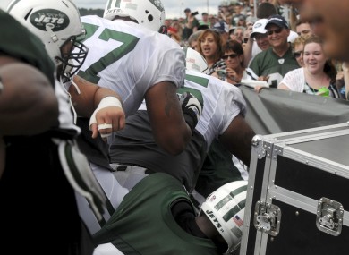 New York Jets players pile up in front of fans during a scuffle.