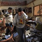 A family walks among debris at their damaged home near Punto Fijo, Venezuela. (AP Photo/Ariana Cubillos/PA)