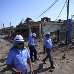 Rescue workers walk past a damaged area on Sunday. (AP Photo/Ariana Cubillos/PA)